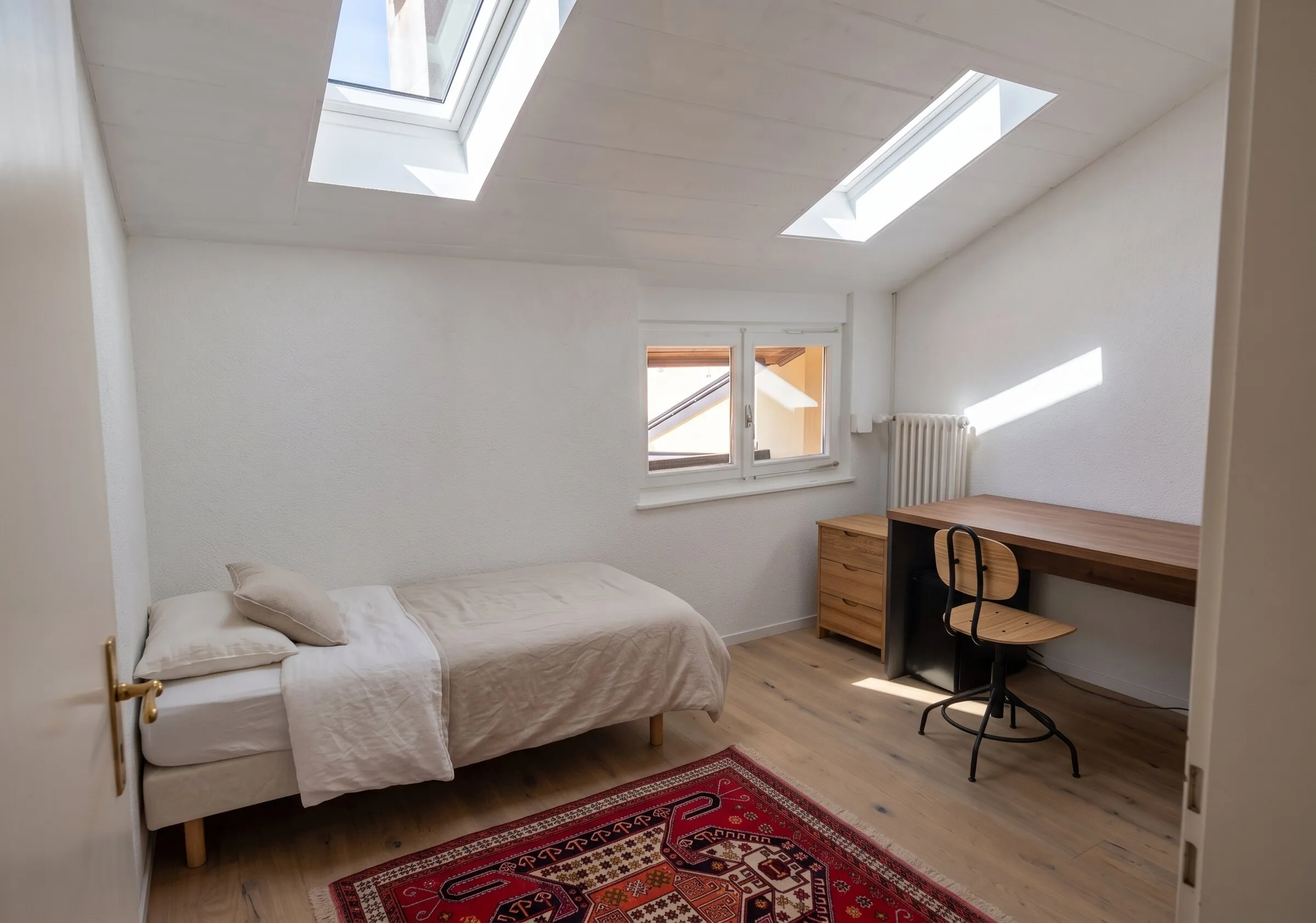 Chambre avec lit et bureau, éclairée par deux velux