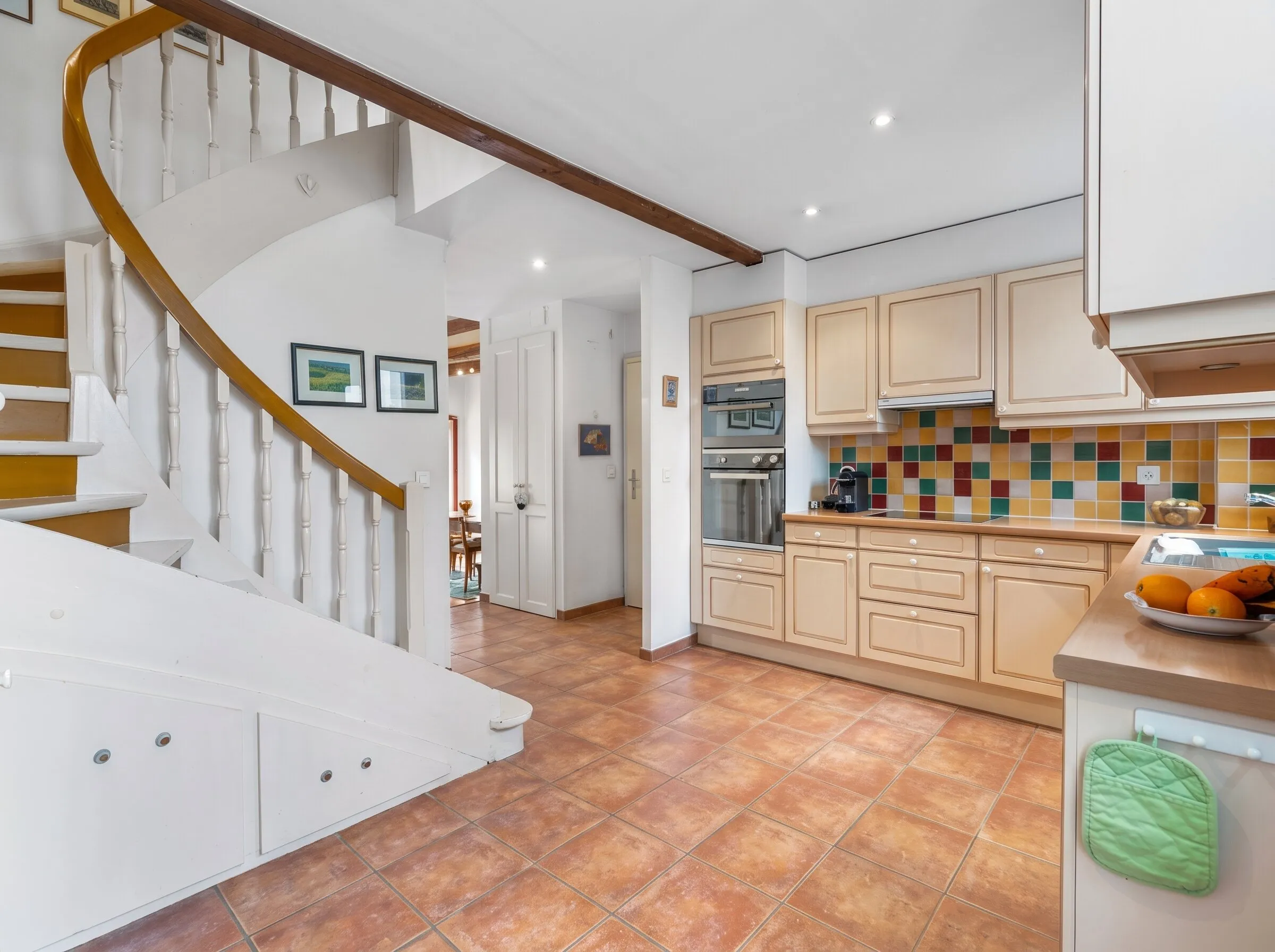 Cuisine équipée avec four et plaques, au pied de l'escalier